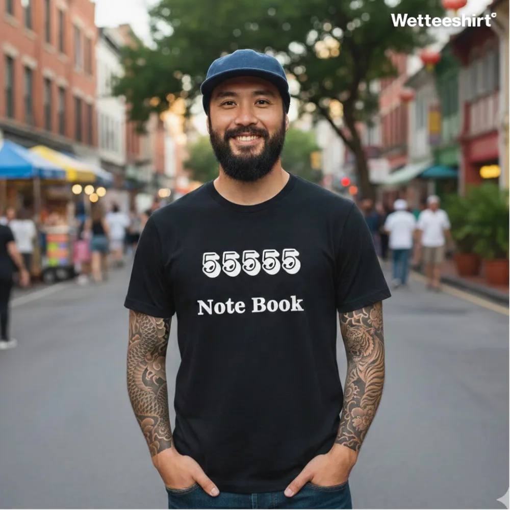 Tattooed man smiling on city street wearing black Wetteeshirt® 55555 Notebook graphic tee, bold five 5s design with ‘Note Book’ text, trendy unisex Singapore streetwear fashion.