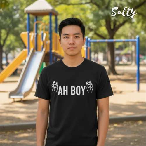 Singapore streetwear fashion — man in park playground wearing Wetteeshirt® x Salty ‘Ah Boy’ black short sleeve t-shirt with bold white lettering and hand gesture graphics, styled casually for lifestyle look, trendy local tee for urban youth culture.