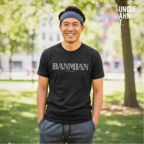 Casual outdoor photo of a man in a black graphic tee with bold white text ‘BANMIAN’ and smaller text ‘PARIS,’ wearing gray pants and a headband, standing in a park with green grass and trees, part of Wet Tee Shirt® x Uncle Ahn T Singapore streetwear collection." Meta description (150 characters): "Banmian Paris tee — sleek black streetwear from Wet Tee Shirt® x Uncle Ahn T, blending bold Singapore vibes with a playful Paris twist.