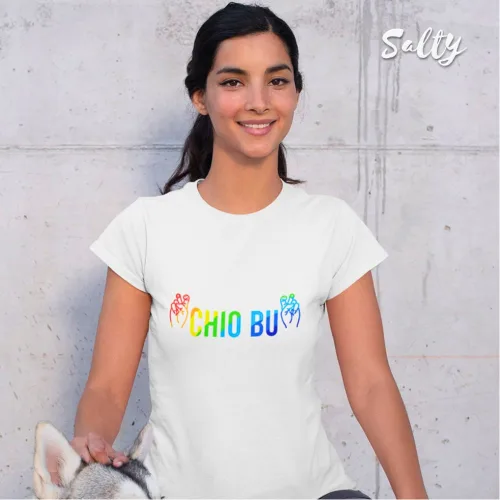 "Playful streetwear photo of a woman with dark hair tied back, sitting against a concrete wall with a dog, wearing a white graphic tee featuring rainbow‑colored text ‘CHIO BU’ and hand symbols, part of the Wet Tee Shirt® x Salty Singapore collection.