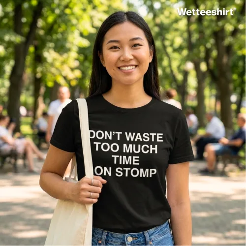 Person carrying tote bag wearing black ‘DON’T WASTE TOO MUCH TIME ON STOMP’ T-shirt, casual unisex streetwear by Wetteeshirt, premium cotton tee with witty Singapore slang design, trendy urban fashion outfit for men and women, cultural statement apparel.