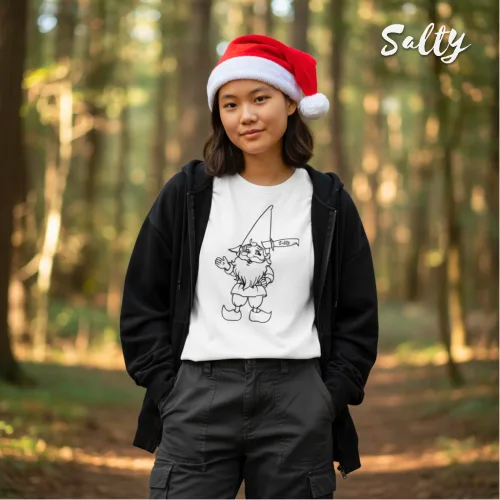 Singapore streetwear — person in forest wearing festive Santa hat, black hoodie, and Wetteeshirt® X Salty white graphic t-shirt featuring cartoon gnome holding candy cane with cheeky rude gesture, lifestyle fashion shot with tall trees and sunlight.