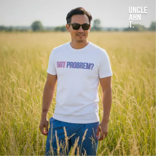 Singapore streetwear GOT PROBREM? white short sleeve T-shirt, playful misspelling in bold blue and pink letters, casual unisex tee by Uncle Ahn T, premium cotton humorous design photographed outdoors in tall grass