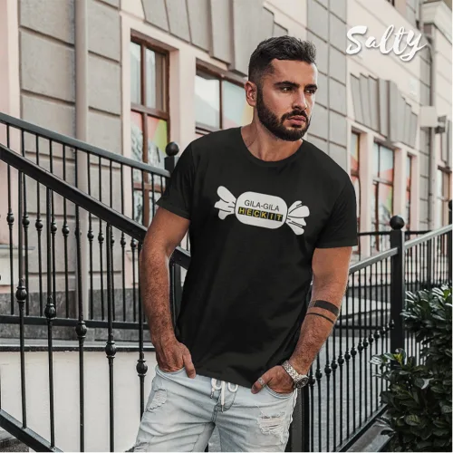 Stylish men’s black graphic t-shirt with bold Heck It print in white and yellow, featuring unique bone design. Urban streetwear fashion shot outdoors with modern railing and building backdrop, perfect for trendy casual outfits. Wet Tee Shirt brand promotional image highlighting edgy Singapore-inspired apparel.