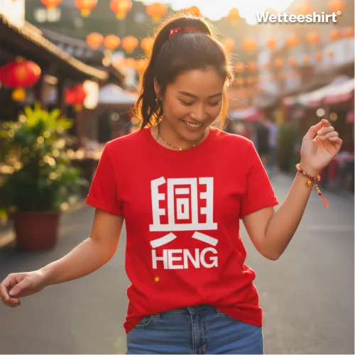 Festive streetwear photo of a person wearing the Wet Tee Shirt HENG red graphic T‑shirt with bold white Chinese character and text, standing in a vibrant outdoor market decorated with red lanterns and warm sunlight — cultural Asian street style casual tee for Chinese New Year celebrations.