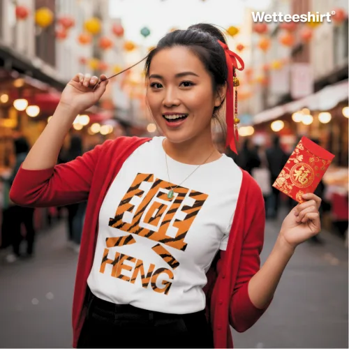 Festive Lunar New Year streetwear photo of a smiling person wearing the Wet Tee Shirt HENG white graphic T‑shirt with tiger stripe design, bold Chinese character, and text, styled with red cardigan and ribbon, holding a traditional red envelope under lantern decorations — cultural Asian street style prosperity tee for celebrations.