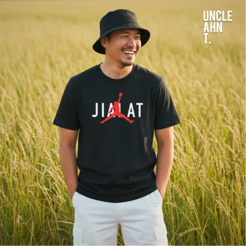Singapore streetwear JIALAT black short sleeve T-shirt, bold white letters with red basketball silhouette graphic, casual unisex tee by Uncle Ahn T, premium cotton playful design photographed outdoors in tall grass