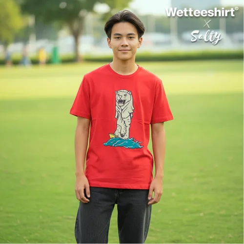 "Singapore streetwear — person in park wearing Wetteeshirt® x Sally red graphic t-shirt featuring upright fish illustration rising from blue waves, casual outdoor lifestyle fashion shot with grassy field and trees in background.