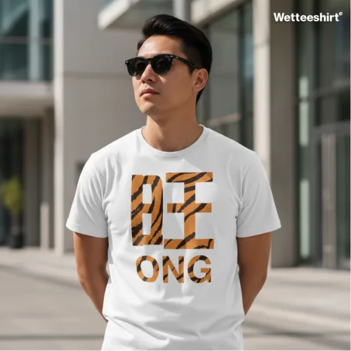 Wet Tee Shirt® Be Ong white T‑shirt with tiger‑stripe ‘BE’ lettering and bold ‘ONG’ typography, styled with sunglasses in modern urban backdrop — playful Singapore streetwear fashion photo.