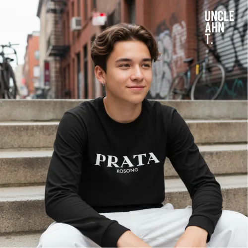 Singapore streetwear PRATA KOSONG black long sleeve T-shirt, bold white text design inspired by local food culture, casual unisex tee by Uncle Ahn T, premium cotton playful design photographed outdoors in urban graffiti street setting