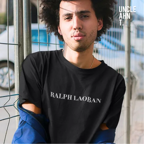 Singapore streetwear RALPH LAOBAN black short sleeve T-shirt, bold white text parody design, casual unisex tee by Uncle Ahn T, premium cotton playful design photographed outdoors in urban street setting