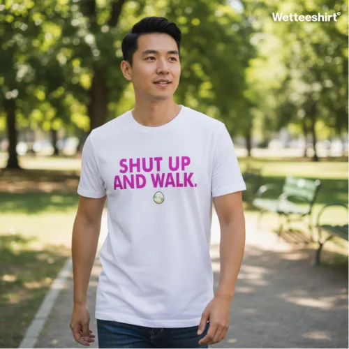 Wet Tee Shirt® Shut Up and Walk white T‑shirt with bold pink typography, styled outdoors in park setting with trees and benches — playful Singapore streetwear lifestyle fashion photo.