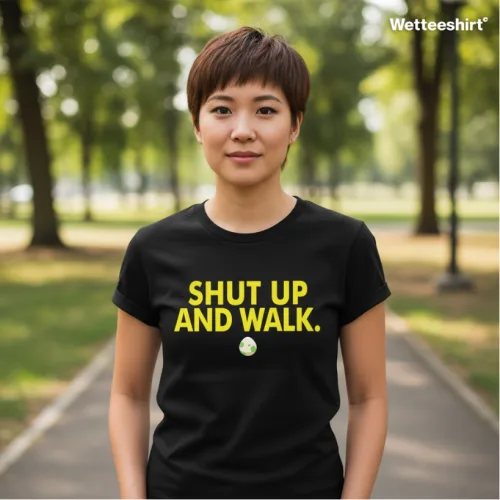 Wet Tee Shirt® Shut Up and Walk black T‑shirt with bold yellow typography and circular graphic, styled outdoors on tree‑lined path — edgy Singapore streetwear lifestyle photo.