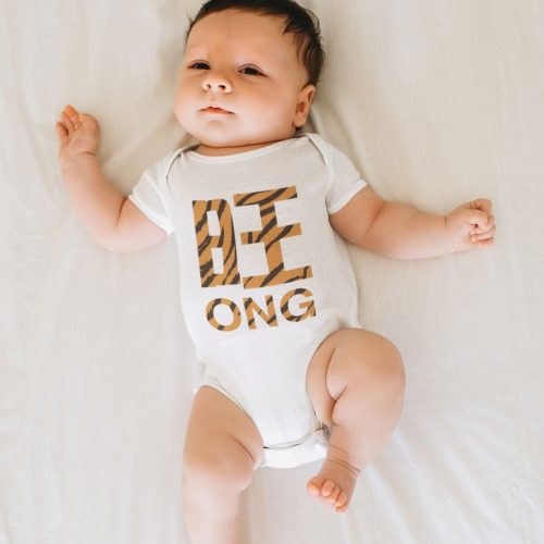 mockup-tiger-of-a-baby-wearing-a-onesie-and-laying-on-a-white-sheet.jpg