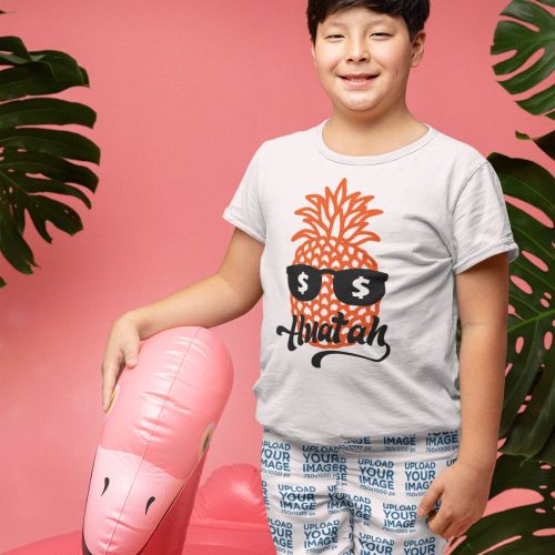 swim-trunks-mockup-of-a-happy-boy-standing-next-to-a-pool-float-and-wearing-a-tee.jpg